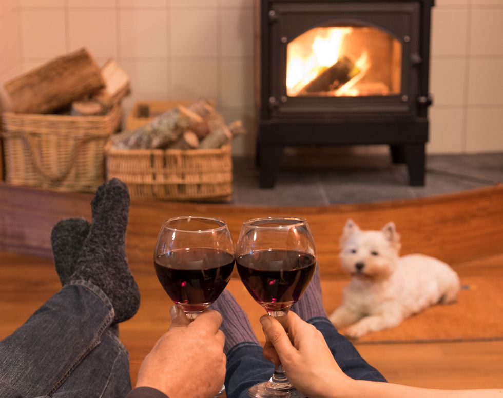 Two people drinking wine infront of a fire